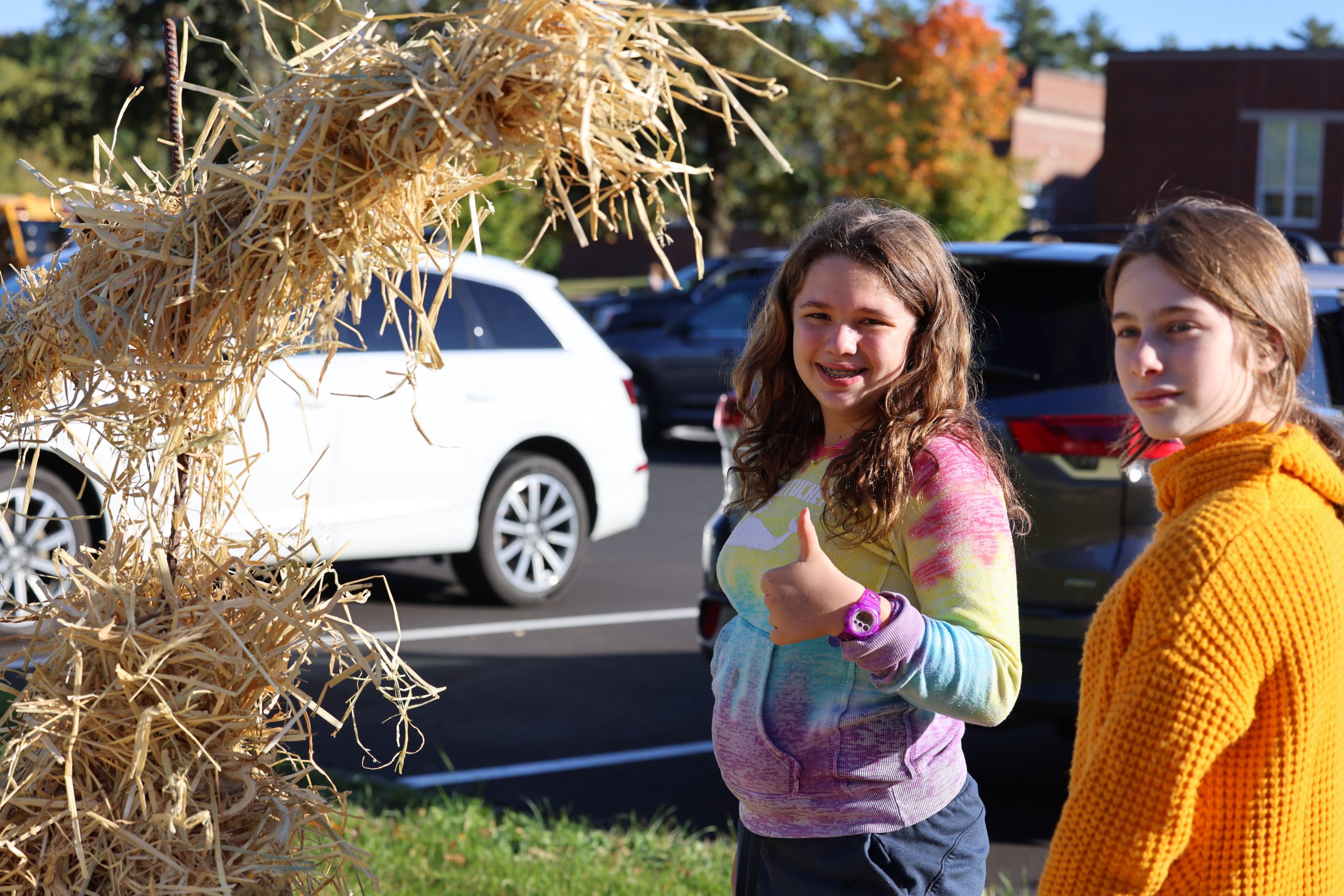 students pose next to scarecrow