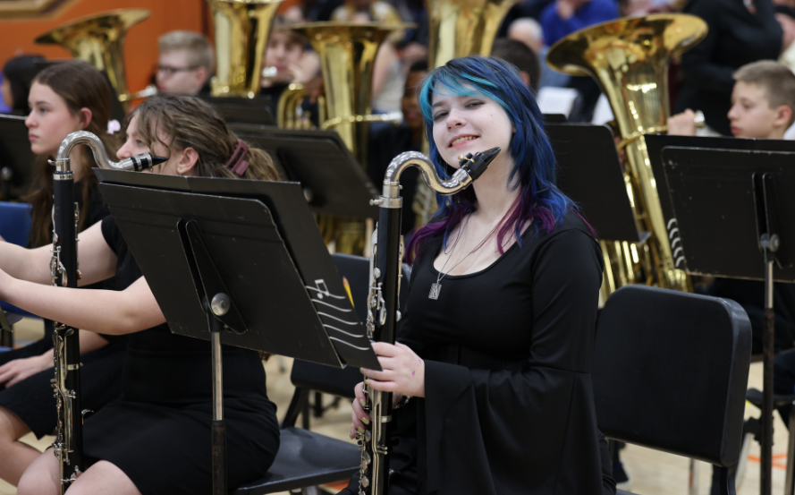 student holding instrument and smiling